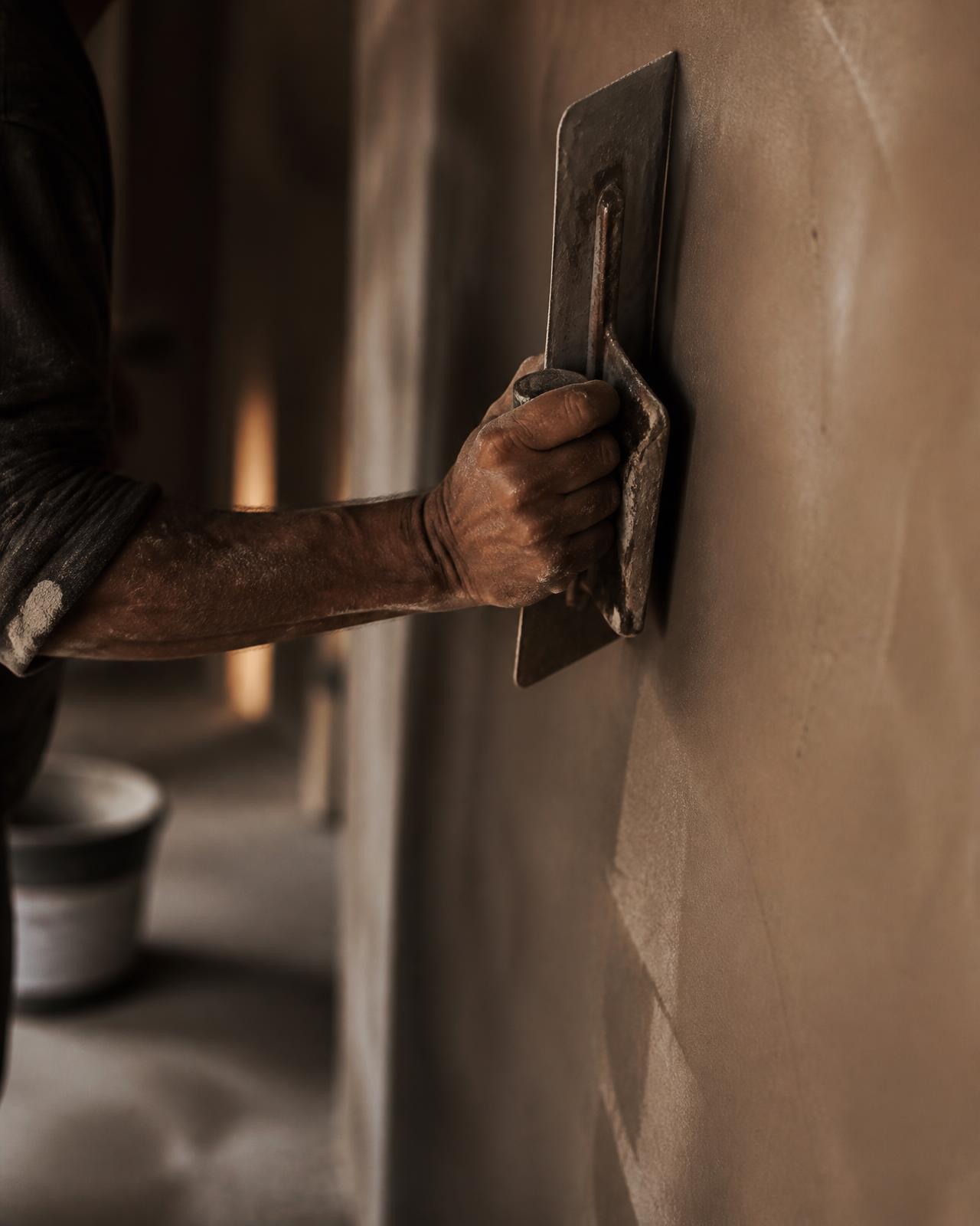 Vakman werkt stucwerk glad met een stalen spaan